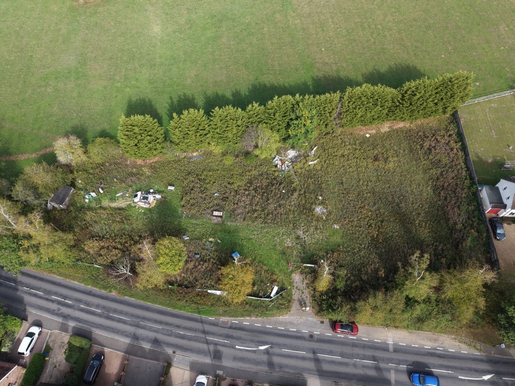 Lot: 26 - LAND IN FAVOURED LOCATION WITH OUTLINE PLANNING FOR SIX DWELLINGS - Aerial view showing road and land